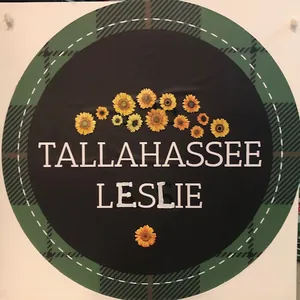 Circular logo with plaid border, sunflowers, and text "Tallahassee Leslie" on a black background.