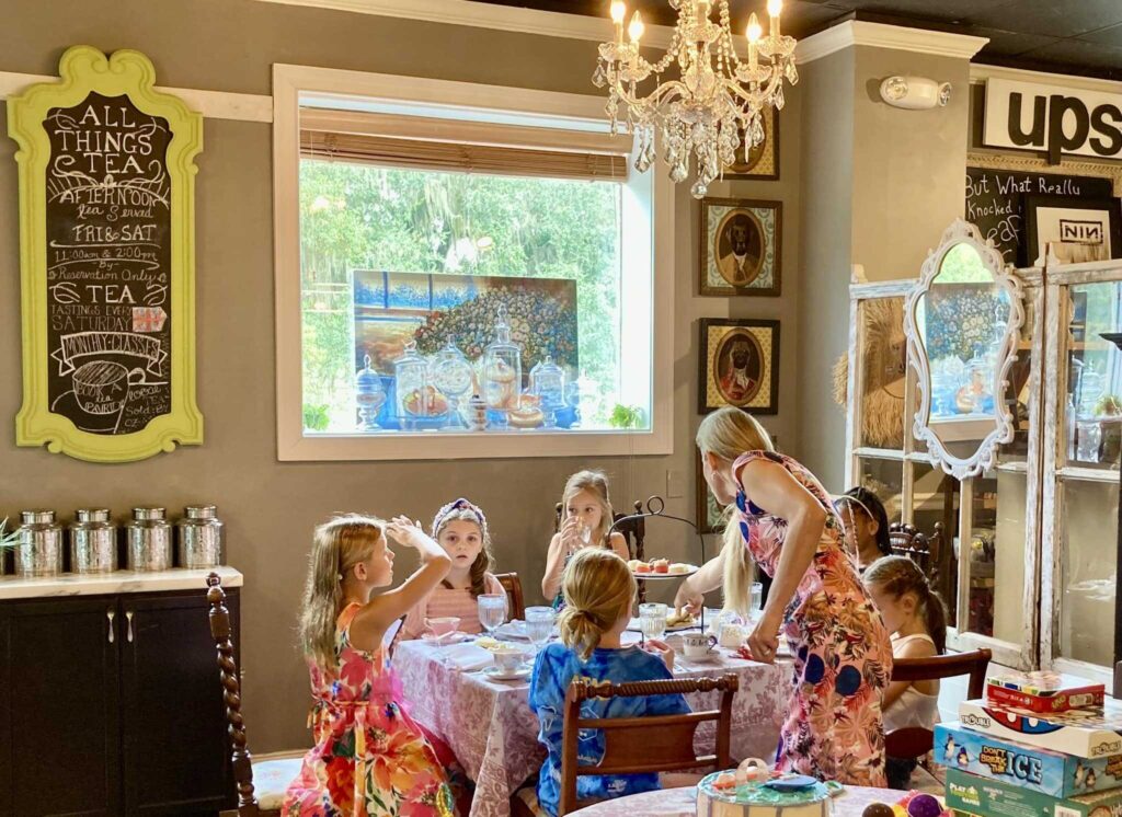 Children enjoying a tea party in a vintage-style tea room with chandeliers and playful decor.